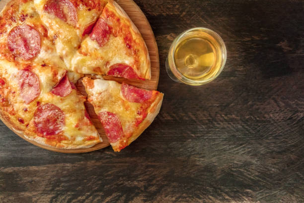 istock Pepperoni pizza with slice cut off, white wine, and copyspace 824299444