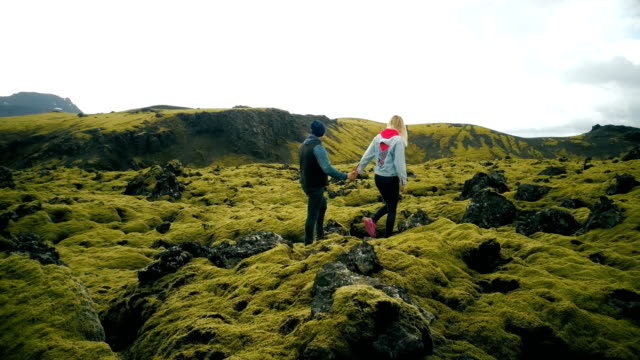 Aerial view of young couple walking on the volcanic lava field in Iceland. Man and woman enjoying the landscape