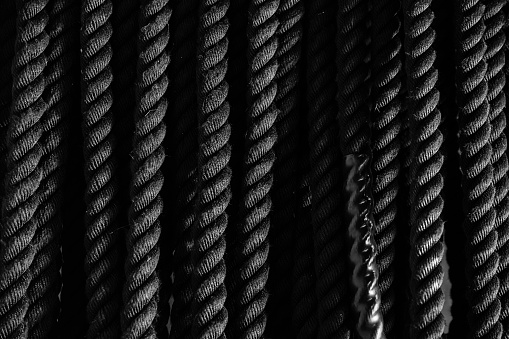 Many black ropes hang on the crossbar in the gym. Texture, background. Atmosphere frame motivation, a place for your text.