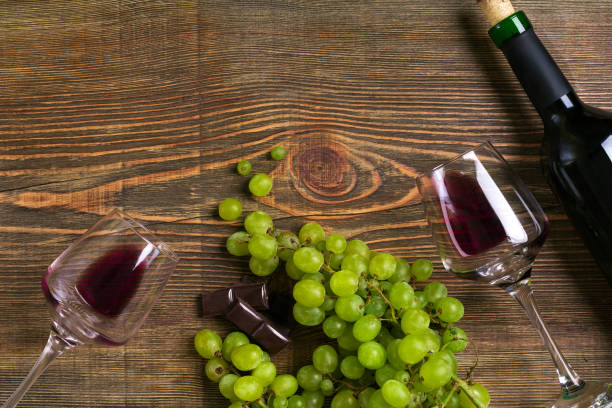 istock Red wine bottle, grape, chocolate and glasses over wooden table. Top view with copy space 824333792