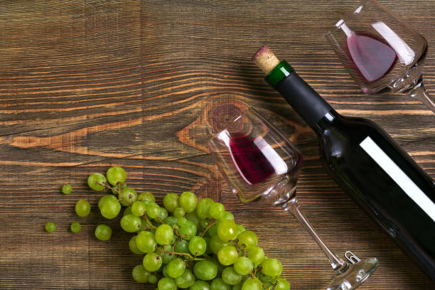 istock Red wine bottle, grape, chocolate and glasses over wooden table. Top view with copy space 824337166