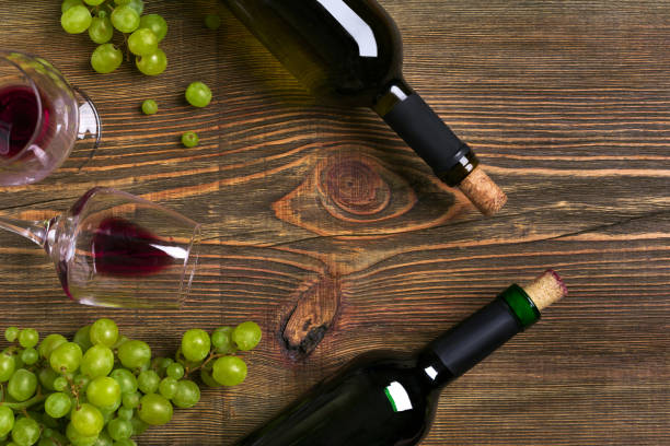 istock Red and white wine bottles, grape and glasses over wooden table. Top view with copy space 824341232