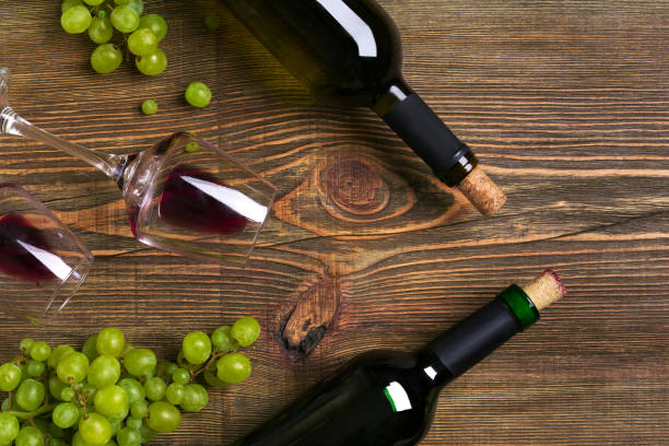 istock Red and white wine bottles, grape and glasses over wooden table. Top view with copy space 824341514