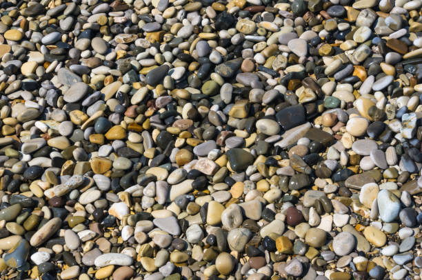 istock sea pebble beach with multicoloured stones, waves with foam 824345104