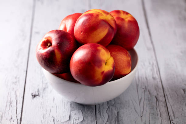 Bowl Of Nectarines Nectarines sitting in a bowl that is sitting on wooden slats nectarine stock pictures, royalty-free photos & images