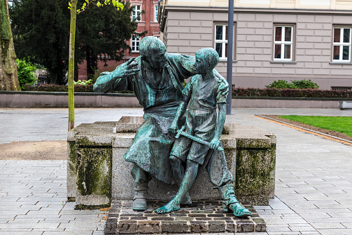 Bronze statute of a man talking to a child holding a sword in Dusseldorf, Germany
