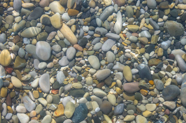 istock sea pebble beach with multicoloured stones, waves with foam 824359654