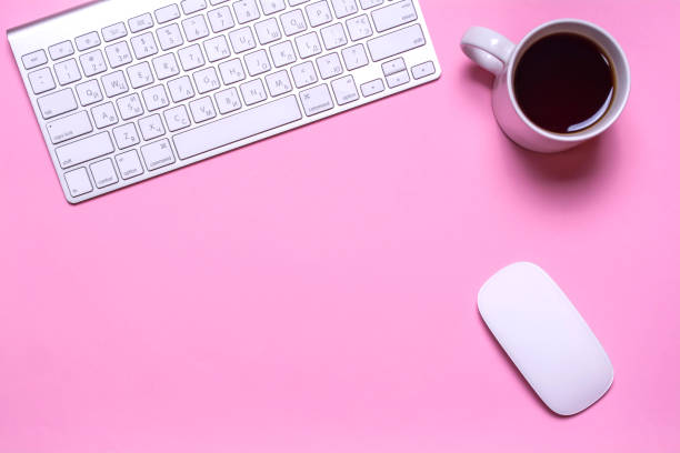 istock Office workplace with keyboard, a cup of tea and a computer mouse on a pink background. 824359832