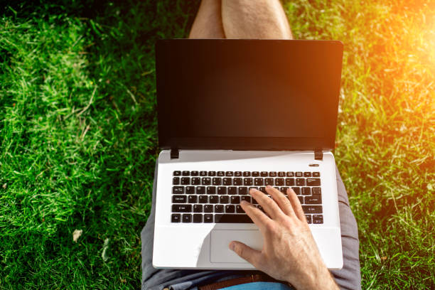 istock Cropped shot of man using laptop with blank screen while sitting on green grass 824366864