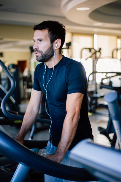 istock Young man at treadmill listening music 824370364