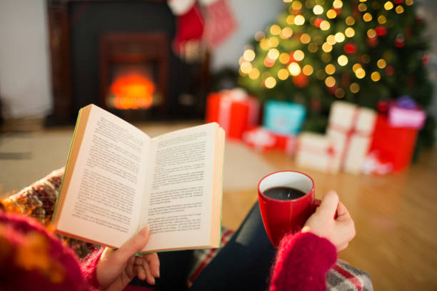 Woman reading a book and drinking coffee at christmas stock photo