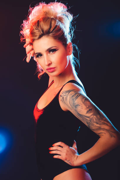 Beautiful female model posing at studio in the light flashes Portrait of sexy tattooed woman posing in the light flashes in studio black pin up girl tattoos stock pictures, royalty-free photos & images
