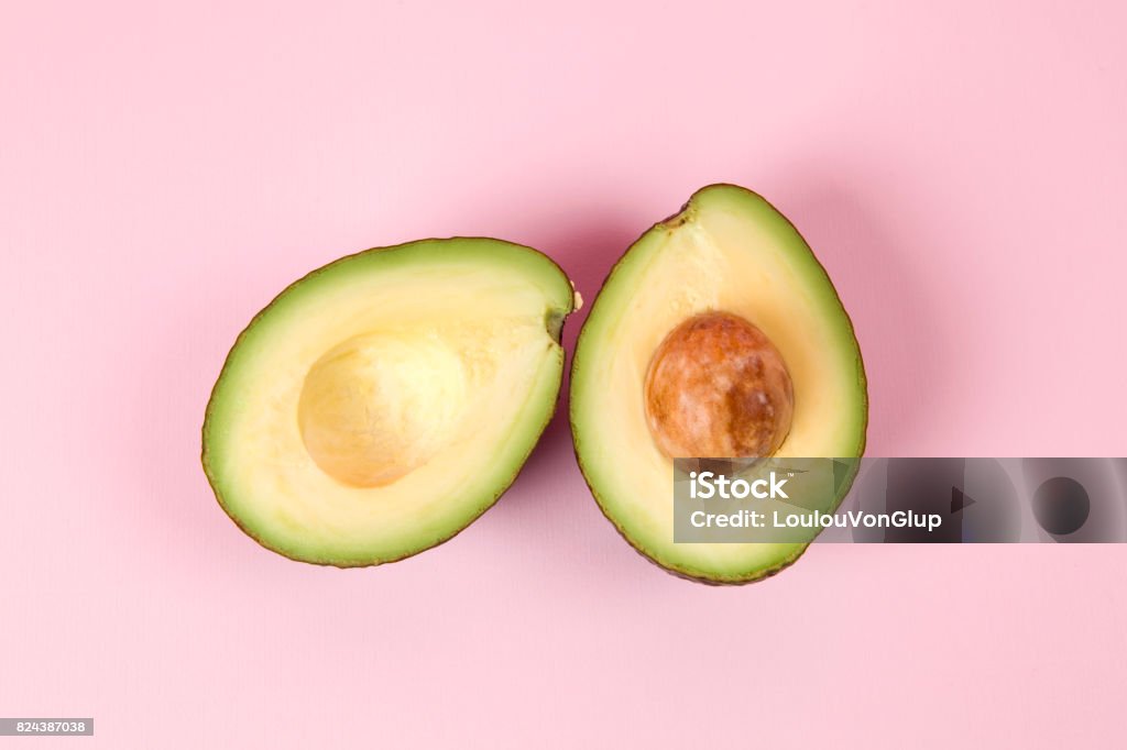 Pink avocado two avocado half with seed on a pink background. minimal color still life photography Avocado Stock Photo
