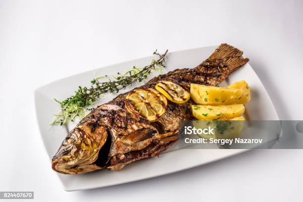 Grilled Carp Fish With Rosemary Potatoes And Lemon Close Up Stock Photo - Download Image Now