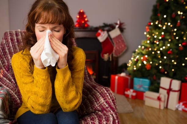 Woman sitting on sofa and blowing her nose at christmas stock photo