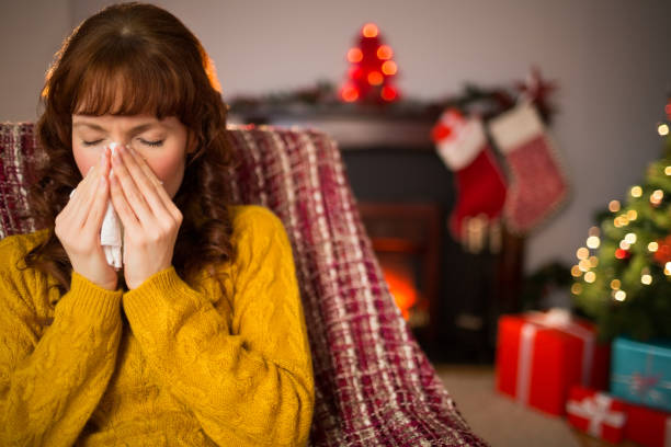 istock Woman sitting on sofa and blowing her nose at christmas 824552276