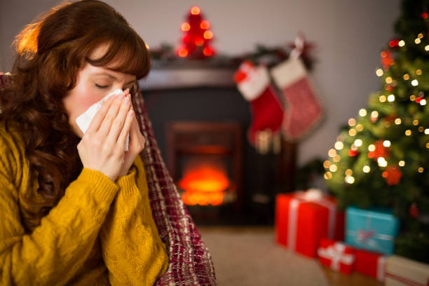 istock Woman sitting on sofa and blowing her nose at christmas 824552302