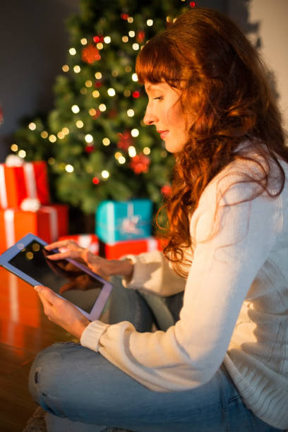 istock Redhead woman sitting on floor using tablet at christmas 824553772
