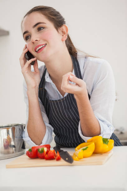istock Pretty brunette on the phone while cooking 824556136