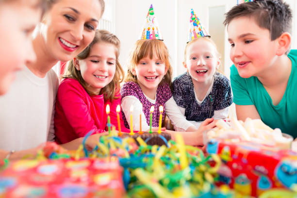 istock Child on birthday party blowing candles on cake 824566276