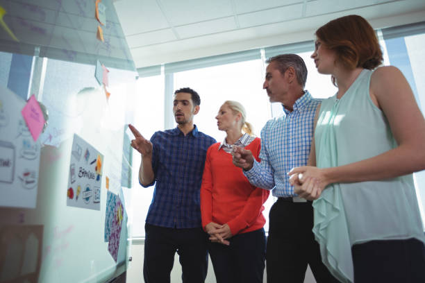 istock Low angle view of business entrepreneurs discussing over whiteboard at office 824580426
