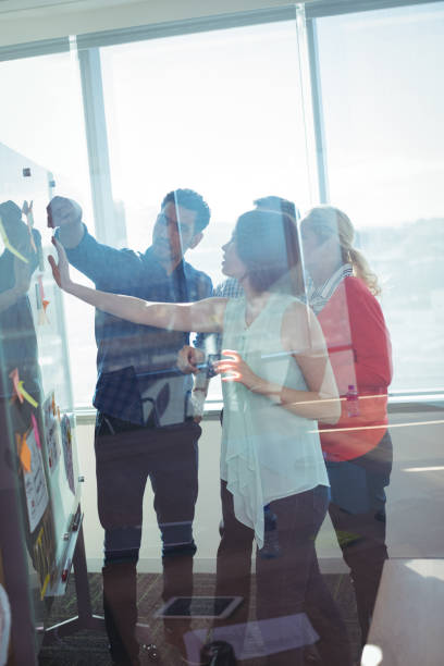 istock Business entrepreneurs seen through glass discussing over whiteboard 824580558