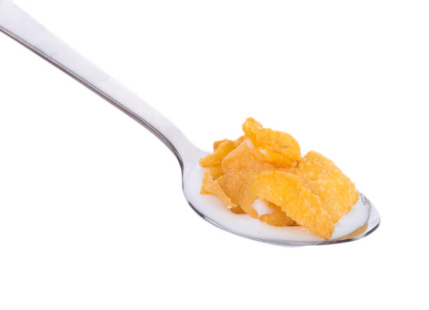 istock Corn flakes with milk in spoon on white background 824582476