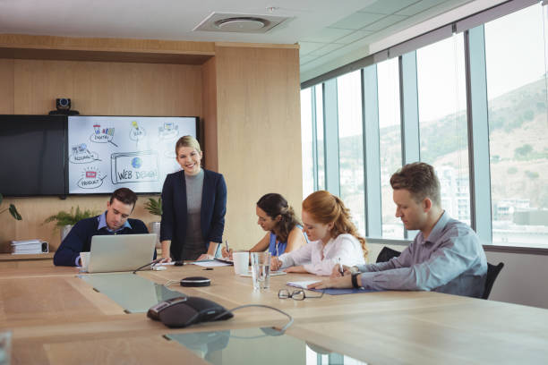 istock Smiling businesswoman with team working at conference table 824588366