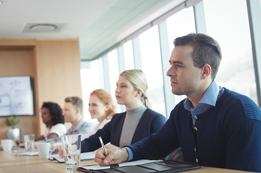 Concentrated business people sitting at conference table during meeting in board room
