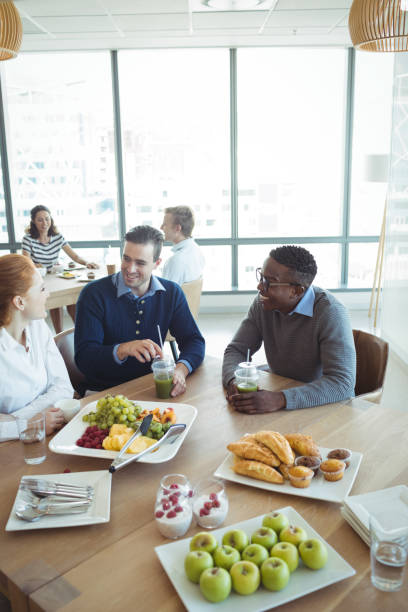 istock Smiling business colleagues having breakfast at office cafeteria 824588832