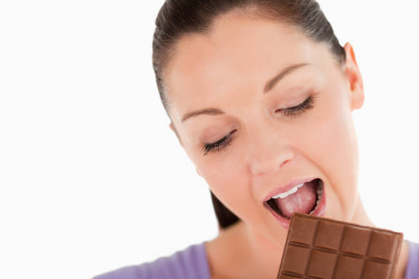 istock Portrait of a charming woman eating a chocolate block while standing 824609996