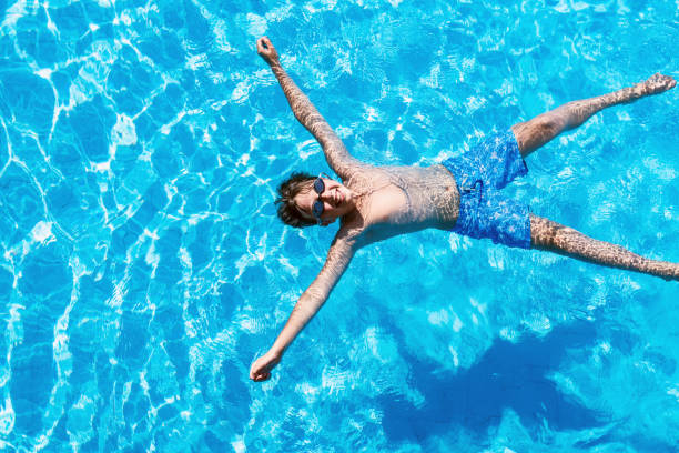 istock Happy boy floating in the swimming pool 824611270