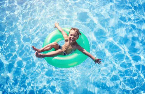 istock Happy boy floating on swim ring in the swimming pool 824611302