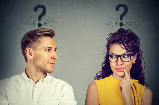Man and woman with question mark looking at each other with interest stock photo