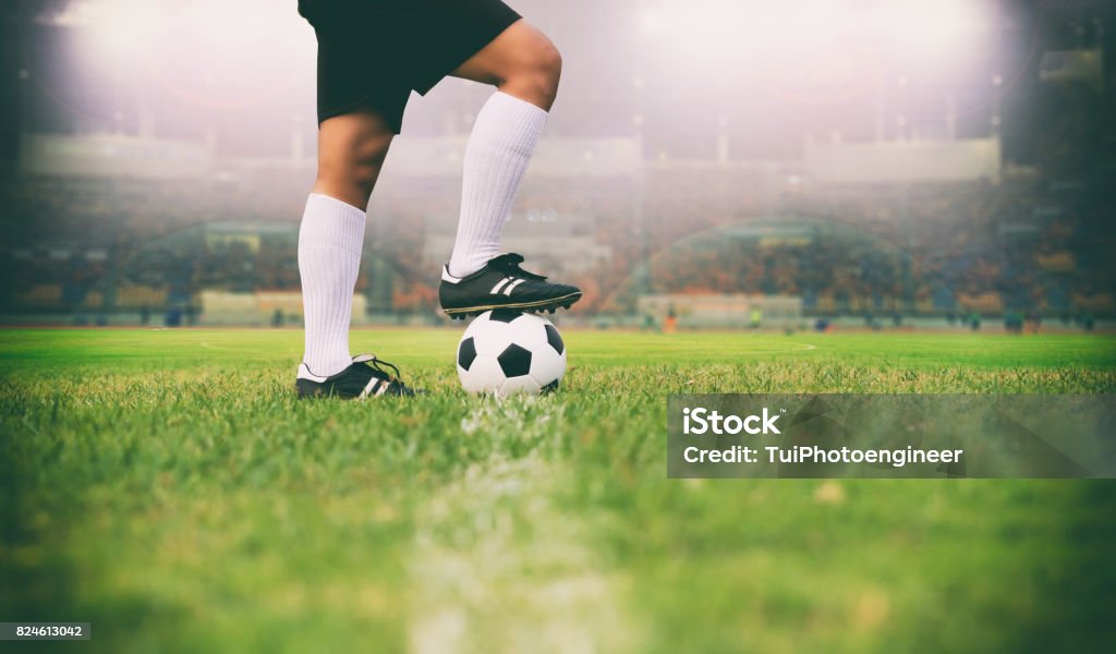 サッカーまたはフットボール プレーヤーのキックのフィールド上のボールを持って立っているサッカー ボール ソフト フォーカスと草の選択と集中 - サッカーのロイヤリティフリーストックフォト