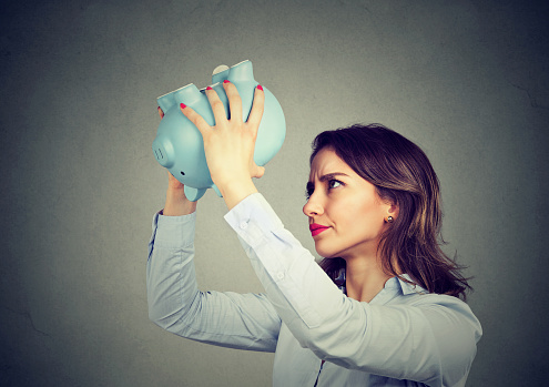 Young worried woman with empty piggy bank