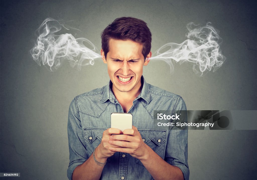 Homme en colère frustré, lire un message texte sur son smartphone souffle vapeur sortant des oreilles - Photo de Frustration libre de droits