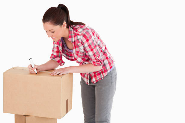 istock Attractive woman writing on cardboard boxes with a marker while standing 824618172