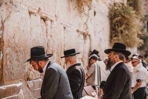 Jews Praying at Western Wall Jerusalem, Israel - November 1st, 2016: Jewsih orthodox belivers reading Torah and praying facing Western Wall, also known as Wailing Wall or Kotel in Old City in Jerusalem, Israel. It is small segment of the structure which originally composed the western retaining wall of the Second Jewish Temple atop the hill known as the Temple Mount to Jews and Christians. rabbi photos stock pictures, royalty-free photos & images