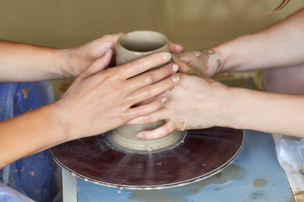 istock Hands of two people create pot, potter's wheel. Teaching pottery 824632352