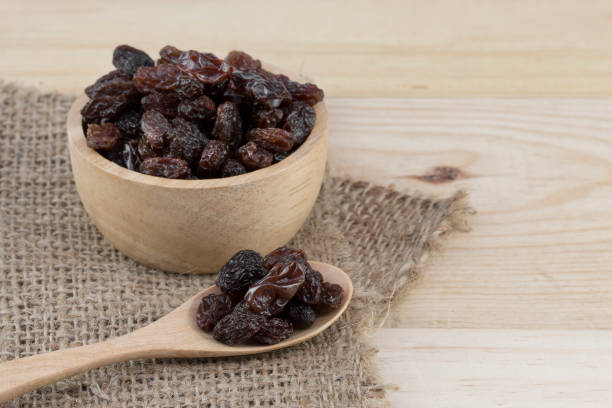 istock raisins in spoon with raisins in bowl on wooden table. 824633596