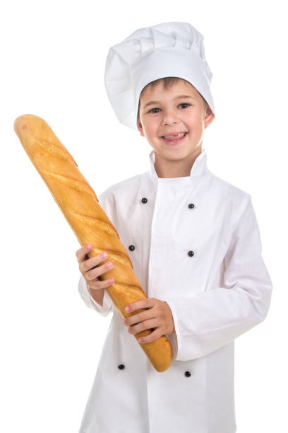 istock Little funny boy dressed in chef uniform with fresh baguette. 824633900