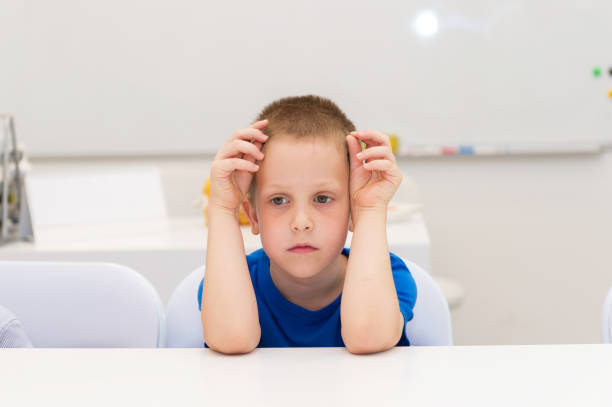 un niño de preescolar se sientan en el escritorio - furious blue little boys caucasian fotografías e imágenes de stock