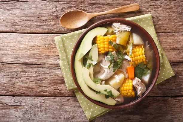 Photo of Traditional Colombian ajiaco soup close up in a bowl. horizontal top view