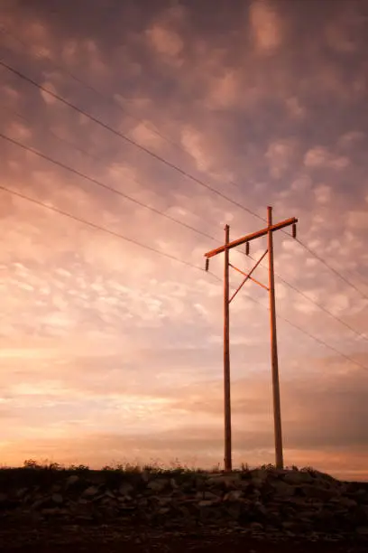 Power or Electrical lines at sunrise or sunset with clouds lighting up the sky