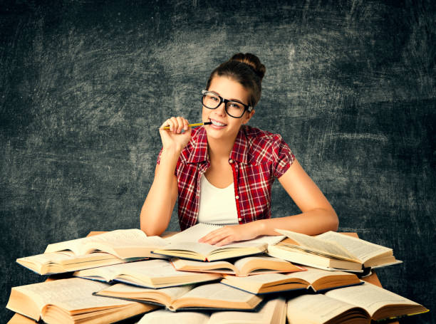 étudiant étudiant livres, faculté de la jeune femme lire beaucoup de livre sur tableau noir - book working college student classroom photos et images de collection