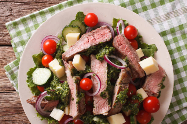 istock Salad vegetables, cheese and beef steak with chimichurri sauce closeup. horizontal top view 824643034