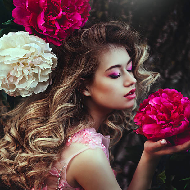 Beautiful sensual blonde woman posing near peony flowers. Girl with long healthy hair and clean skin. Creative colors and Artistic processing. Beautiful sensual blonde woman posing near peony flowers. Girl with long healthy hair and clean skin. victoria beckham stock pictures, royalty-free photos & images