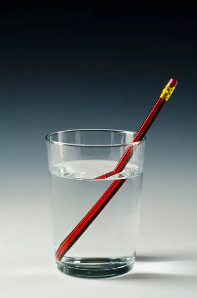 A pencil in a glass of water shows light refraction.