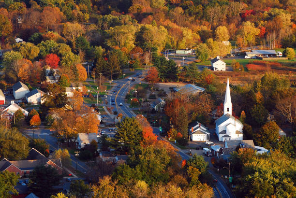 Aerial of a New England Village The fall foliage surrounds a quaint New England village in an aerial photogrph charming stock pictures, royalty-free photos & images